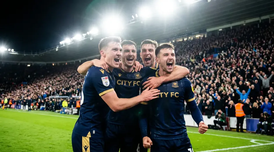 Joueurs de football en maillots bleus célébrant un but ensemble sur la pelouse d'un stade international